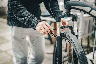A young man pulls a brake cable on the handlebars of a bicycle.