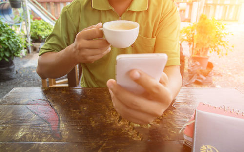 Midsection of man holding coffee cup on table
