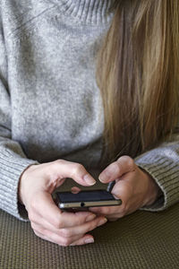 Young woman holds smartphone in her hands. she browses information on mobile phone screen.