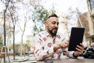 Young bearded businessman sitting at table,using tablet computer