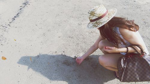 Side view of woman crouching at beach