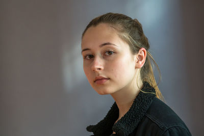 Portrait of young woman looking away against wall