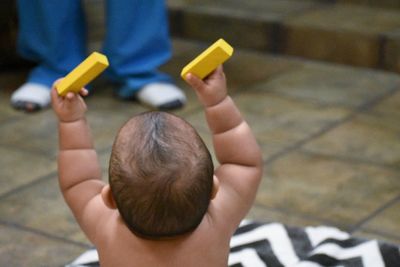 Rear view of boy holding baby while sitting outdoors