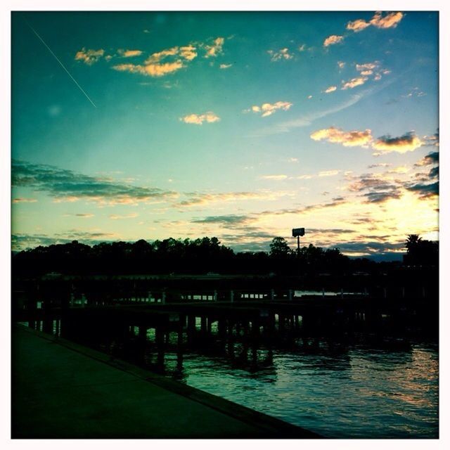 transfer print, sky, water, sunset, auto post production filter, cloud - sky, built structure, river, architecture, tranquility, cloud, tranquil scene, scenics, building exterior, beauty in nature, tree, nature, silhouette, waterfront, lake