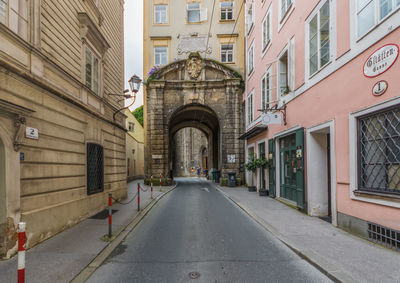 Empty road amidst buildings in city