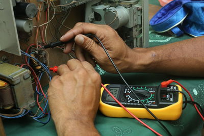 Cropped hands of male technician repairing radio