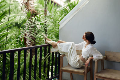 Rear view of woman sitting on railing