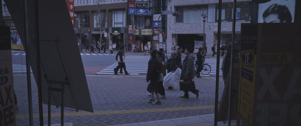 People walking on street amidst buildings in city