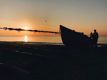 Silhouette man on beach against sky during sunset