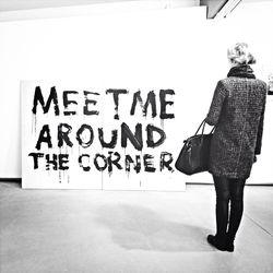 Full length rear view of woman looking at message on wall