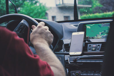 Midsection of man using mobile phone in car