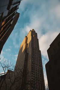 Low angle view of skyscrapers against cloudy sky