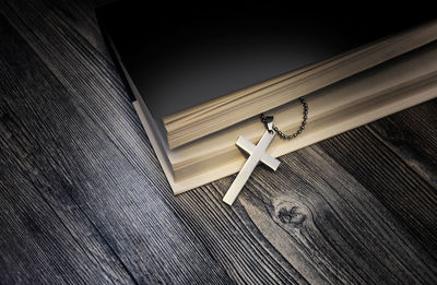 High angle view of cross in book on wooden table