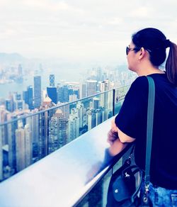 Side view of young woman standing by river against sky