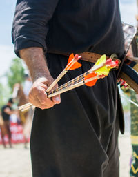 Midsection of man holding arrows while standing outdoors