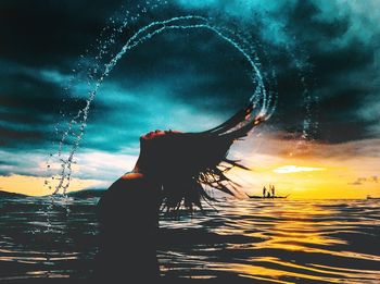 Silhouette woman enjoying in sea against sky during sunset