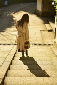 Rear view of woman walking on footpath