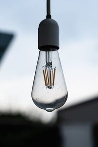 Low angle view of light bulb hanging against sky
