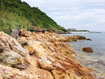 View of rocks in sea against cloudy sky