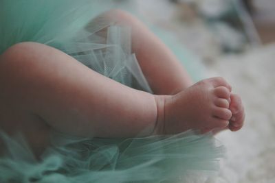 Low section of baby girl lying on bed