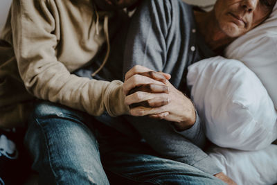 Daughter holding father's hand in bedroom at home