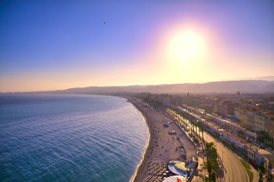 Aerial view of city by sea against sky during sunset