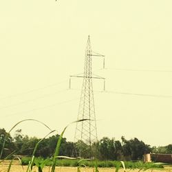 Electricity pylon on field against clear sky