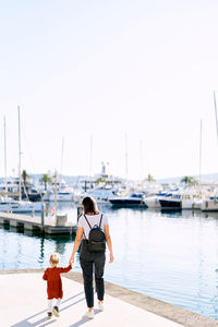 Rear view of woman with daughter near sea against sky