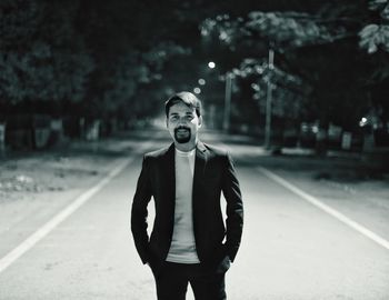 Portrait of young man standing by road in city