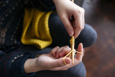 Young woman knitting wool with needle at home