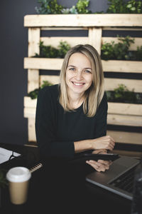 Portrait of smiling young woman sitting on table