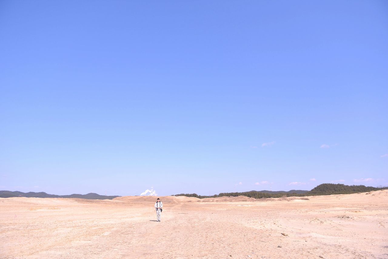 clear sky, copy space, blue, sand, landscape, tranquility, tranquil scene, desert, horizon over land, scenics, nature, beauty in nature, arid climate, remote, sand dune, one person, non-urban scene, day, outdoors, solitude