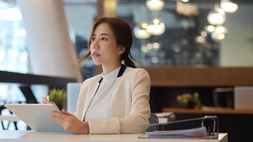 Young woman using mobile phone at table