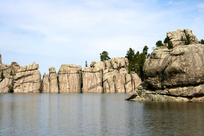 Rock formation by sea against sky