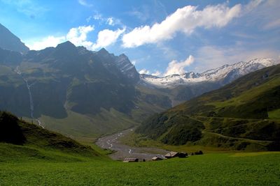 Scenic view of grassy landscape against cloudy sky