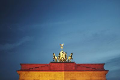 Low angle view of quadriga statue on brandenburg gate against sky