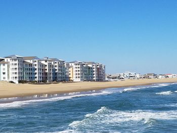 Sea by city against clear blue sky