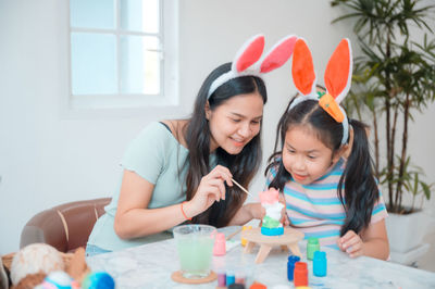 Mother and daughter sitting on table