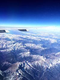 Low angle view of airplane flying over snowcapped mountains