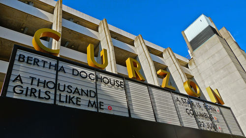 Low angle view of text on building against clear blue sky