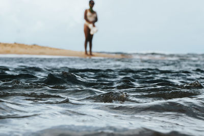 Woman standing on shore at beach against sky