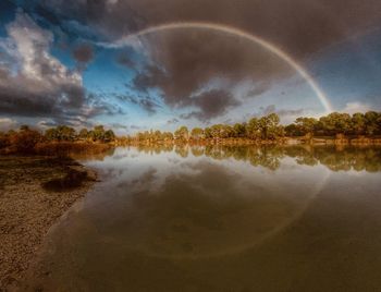 Scenic view of rainbow over lake against sky