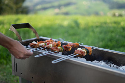 Hand holding meat on barbecue grill