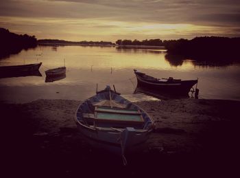 Boats in sea at sunset