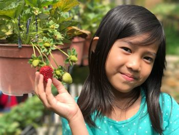 Close-up of smiling girl holding strawberry