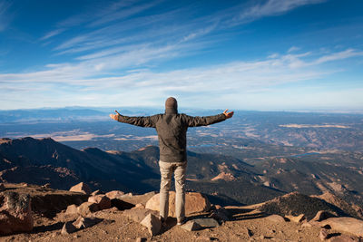 Rear view of man on rock against sky