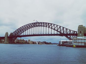View of harbor bridge over river against cloudy sky