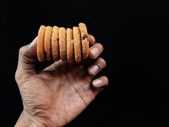 Close-up of hand holding food against black background