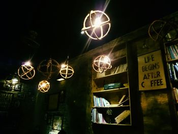Low angle view of illuminated lighting equipment at night