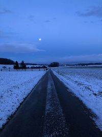 Road amidst snow against sky at dusk